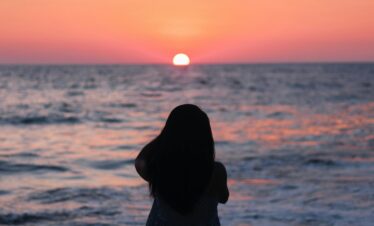 Silhouette of a woman enjoying a vibrant sunset at Acapulco beach.