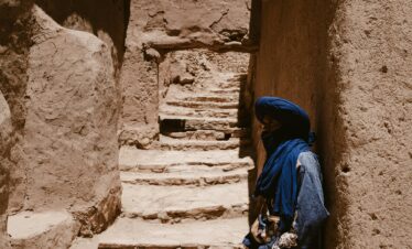 A Berber man in traditional attire stands in the ancient Ksar of Ait Benhaddou, Morocco.