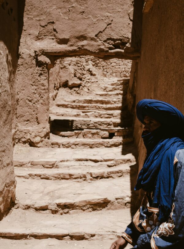A Berber man in traditional attire stands in the ancient Ksar of Ait Benhaddou, Morocco.