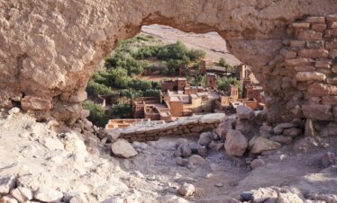 A picturesque view of Aït-Ben-Haddou through ancient ruins, showcasing Morocco's desert architecture.