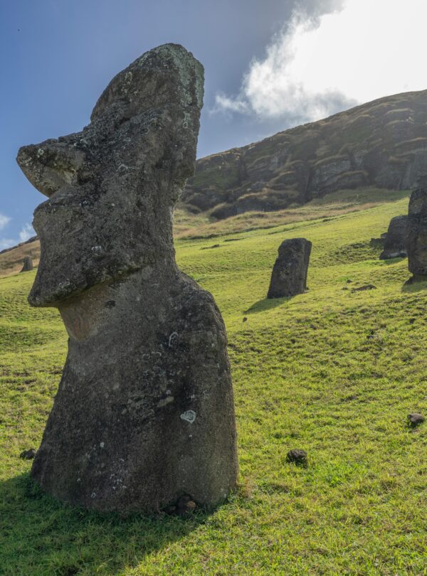 Iconic Moai statues standing on green hills under a bright sky on Easter Island.