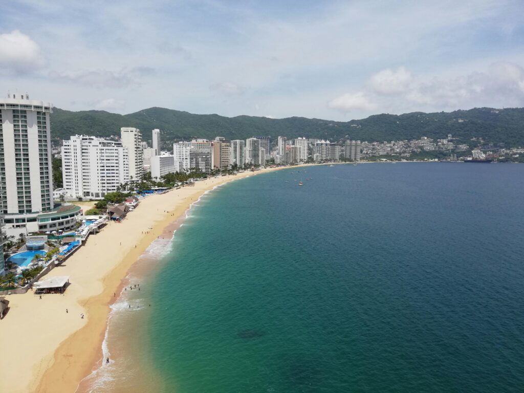 Scenic aerial shot of Acapulco Bay with beachfront resorts and coastline.
