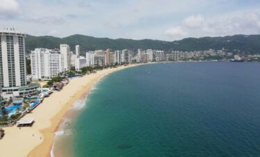 Scenic aerial shot of Acapulco Bay with beachfront resorts and coastline.
